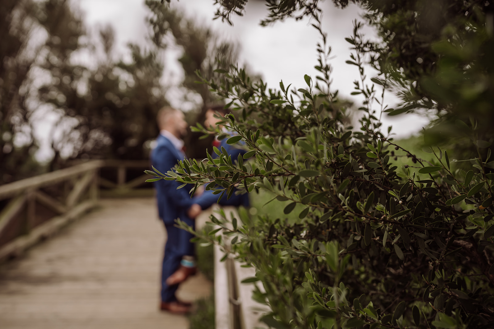 Bay Area Oakland wedding photographer, Xilo Photography, Kati Douglas, took this picture of a same sex gay couple on their wedding day/elopement day as the two grooms pose on a bridge in Fort Funston, CA