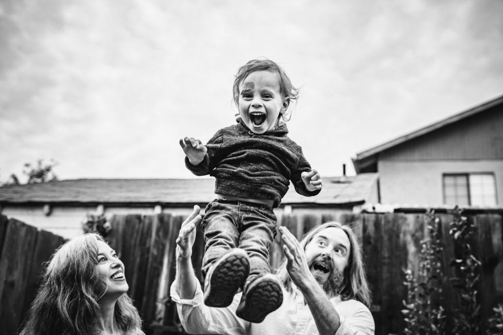 Family of three gets silly in the backyard during family photography session with Xilo Photography