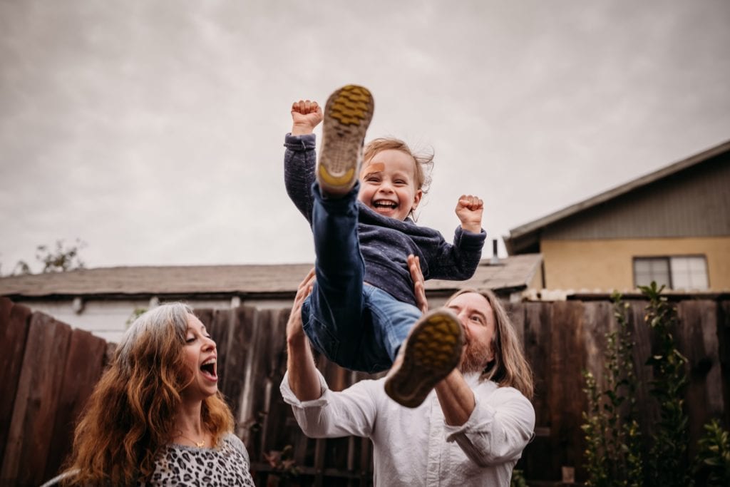 Toddler gets thrown in the air by parents during family photography session with Xilo Photography