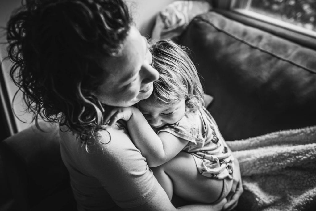 Mama and toddler cuddle closely on couch during a Motherhood Session with Xilo Photography