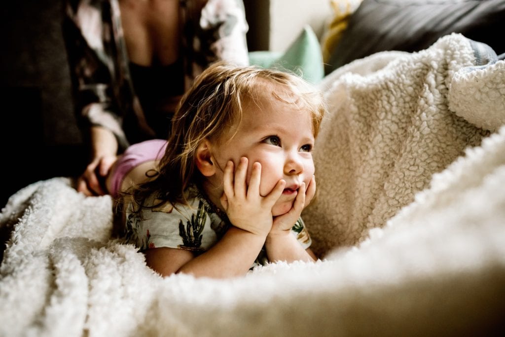 Toddler lays on stomach with their hands on cheeks during a Motherhood Session with Xilo Photography
