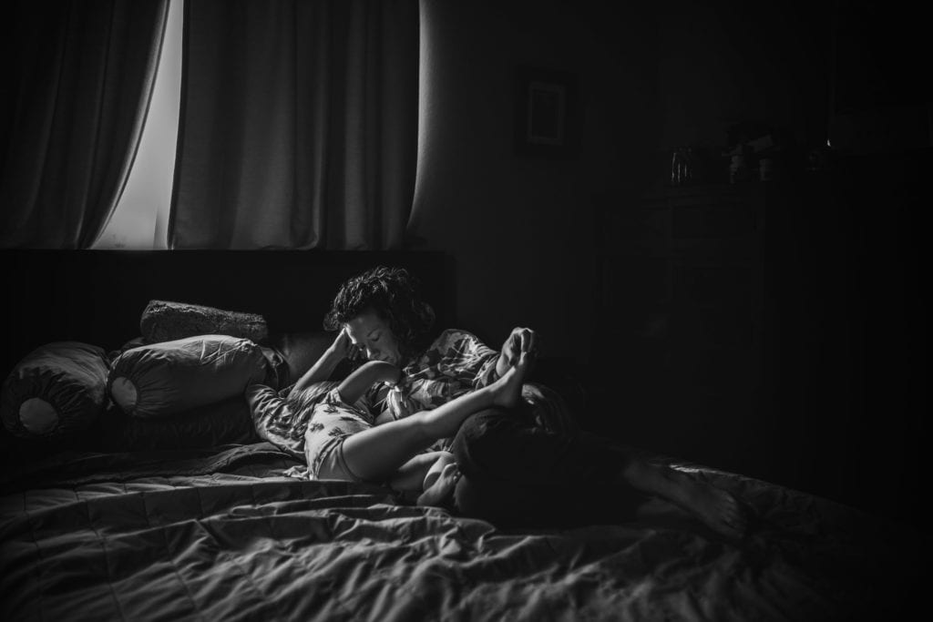 black and white photo of mama and toddler laying together on the bed during a Motherhood Session with Xilo Photography