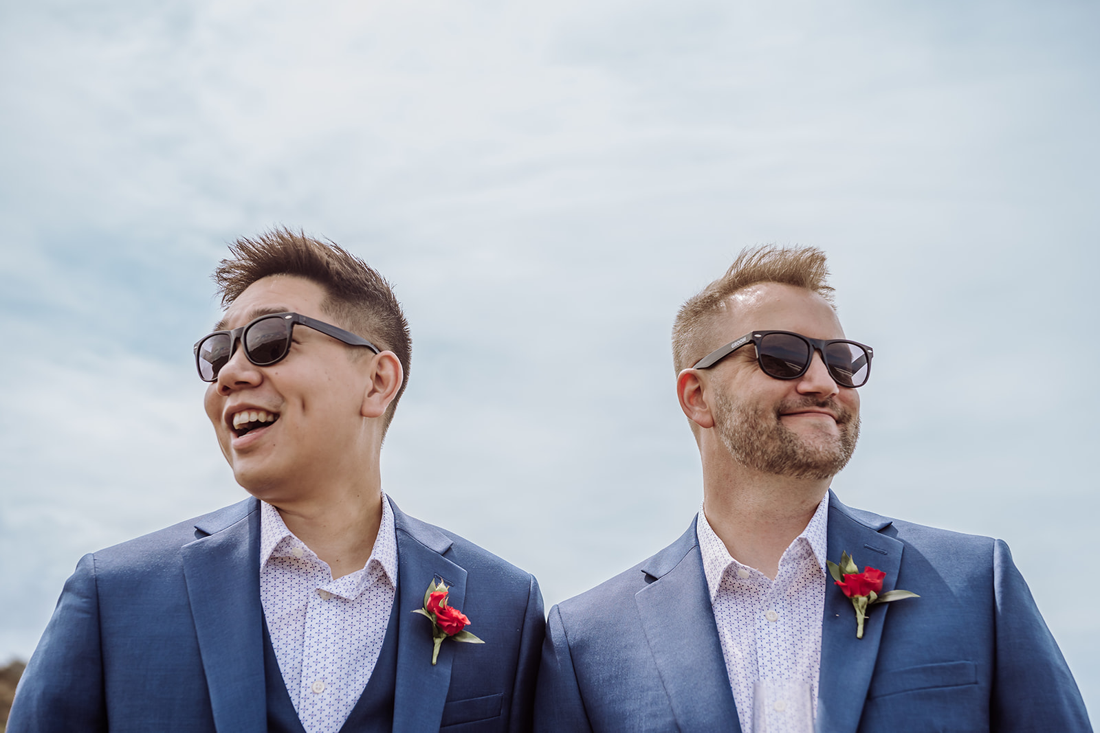 An inclusive intimate wedding and elopement photographer, Xilo Photography, Kati Douglas who is based in Oakland, California in the bay area, took this picture of a same sex gay couple on their wedding day/elopement day as the two grooms pose in their tuxes with sunglasses near the beach at Fort Funston, CA which was their intimate wedding venue. Ever wondered what is an intimate wedding or what would be considered a small wedding? This is a great example of both! 