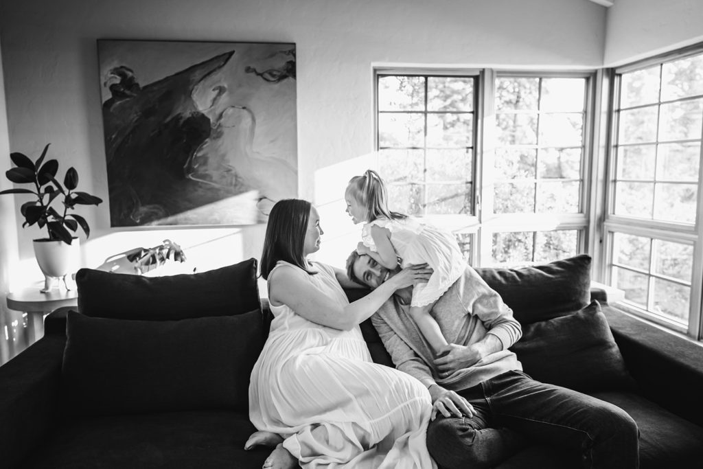 Xilo Photography of San Francisco Bay Area (also based in Oakland, CA) captured this gorgeous black and white with lots of natural light photograph of a mother, father, their adorable daughter and the mother's growing baby bump as they lounge on the couch together. In celebration of her pregnancy they scheduled a maternity photoshoot at home with Kati of Xilo Photography, an inclusive intimate documentary photographer who specializes in capturing emotions and connection in her photos