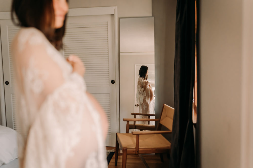 Stunning sheer white lace rope over a pregnant mother's tummy with her reflection in a mirror showing her gorgeous motherhood journey and changing body in this maternity photoshoot in San Francisco Bay Area with Xilo Photography, intimate inclusive documentary photographer