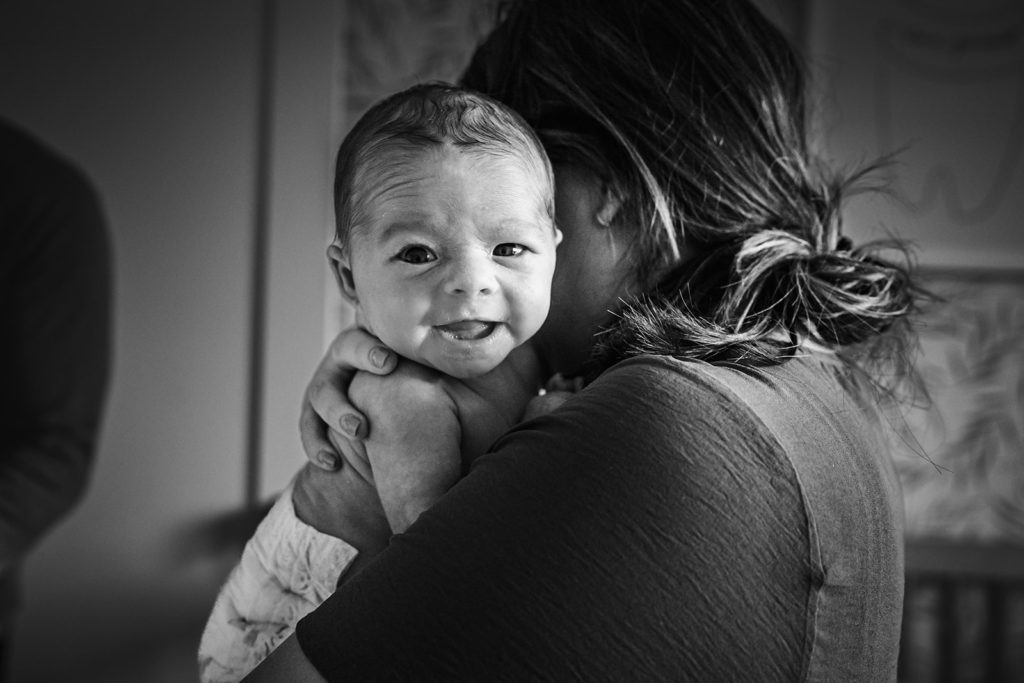Black and white documentary over the shoulder smiling newborn portrait with mother in Bay Area, California by Xilo Photography