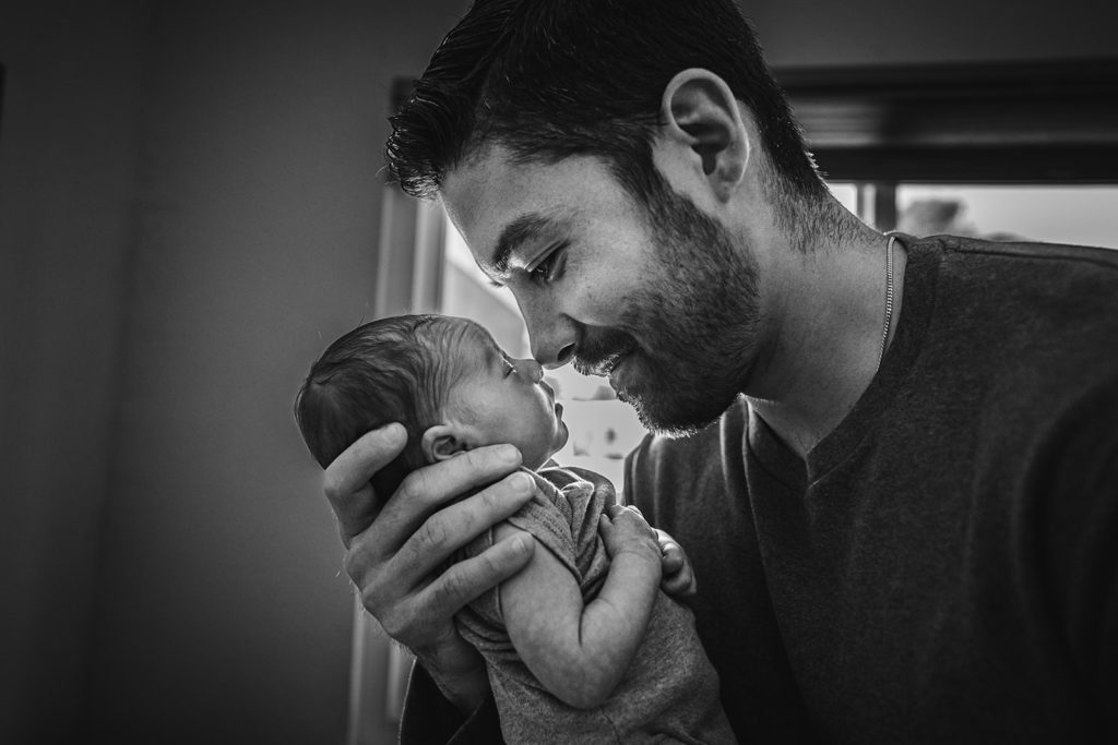 Father and newborn son are in a nose to nose photography pose and bonding during their at home lifestyle and documentary newborn photography session in El Cerrito, CA by Kati Douglas, Documentary Photographer at Xilo Photography